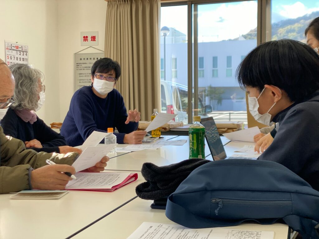 a group of people sitting around a table wearing face masks